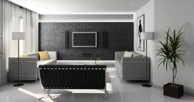 salon moderne minimaliste avec canapé noir, murs gris damassé et tv murale intégrée
