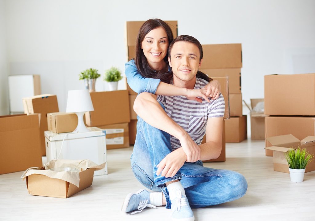 jeune couple heureux entouré de cartons dans leur nouvelle maison lors d'un emménagement