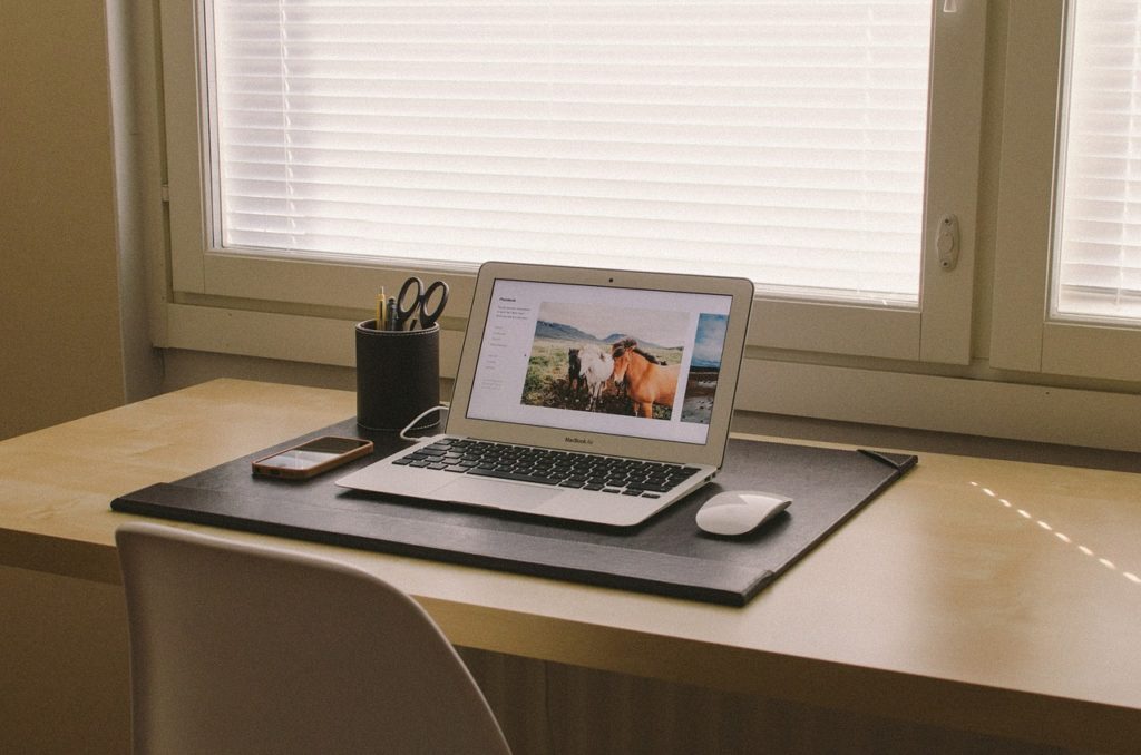 espace de travail minimaliste avec bureau en bois, laptop et accessoires zen devant fenêtre