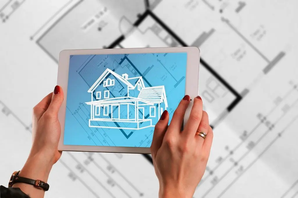 architecte d'intérieur visualisant une maison sur tablette au-dessus de plans
