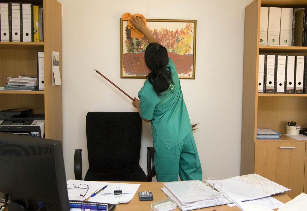 femme en tenue verte nettoyant un tableau dans un bureau minimaliste