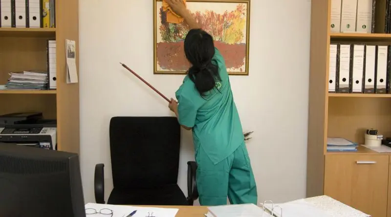 femme en tenue verte nettoyant un tableau dans un bureau minimaliste