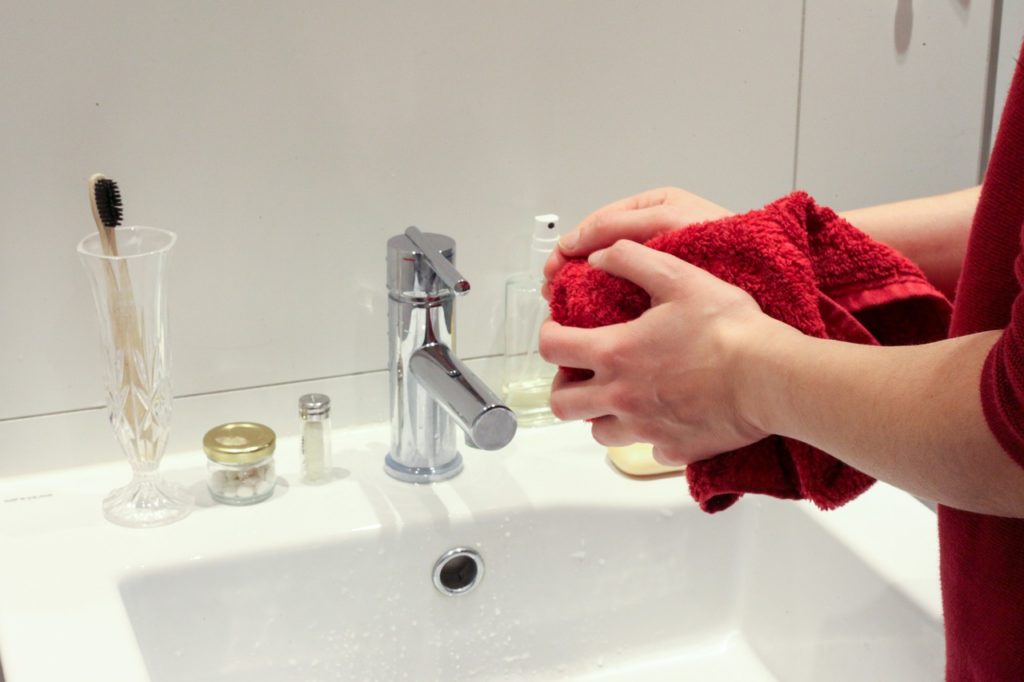 mains séchant avec une serviette rouge devant un lavabo minimaliste