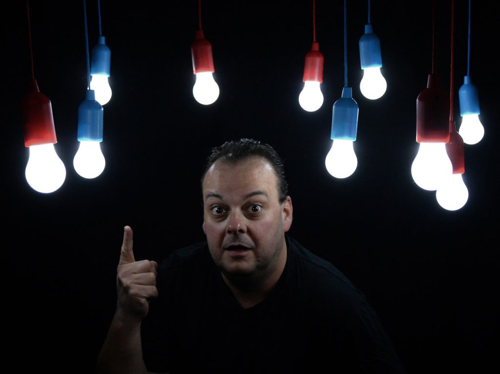 homme enthousiaste pointant vers des ampoules LED colorées suspendues dans l'obscurité