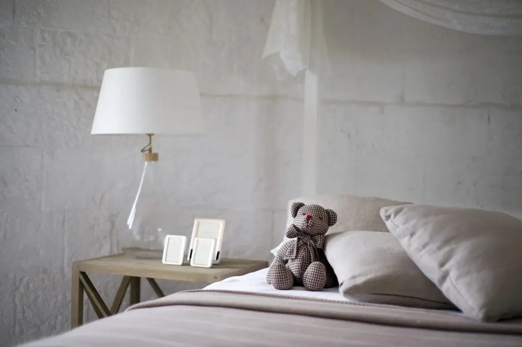 chambre minimaliste zen avec oreillers orthopédiques blancs et teddy bear sur lit