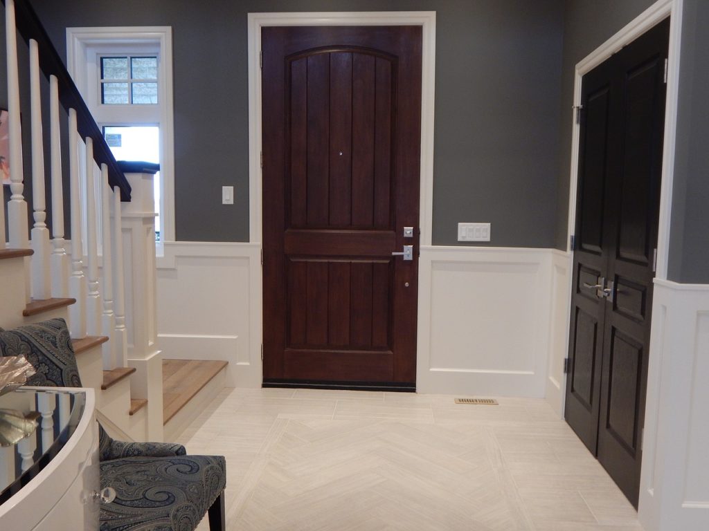 entrée moderne avec escalier blanc, portes en bois foncé et rangements intégrés