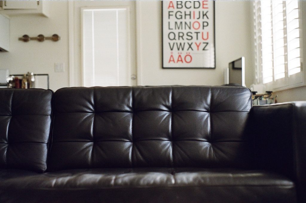 canapé en cuir noir dans un intérieur minimaliste avec tableau alphabet