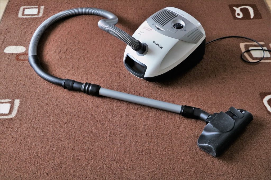 aspirateur compact blanc et gris avec accessoires sur tapis marron