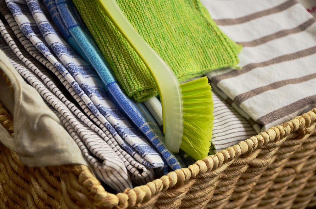 linge de cuisine plié dans un panier en osier avec brosse écologique verte