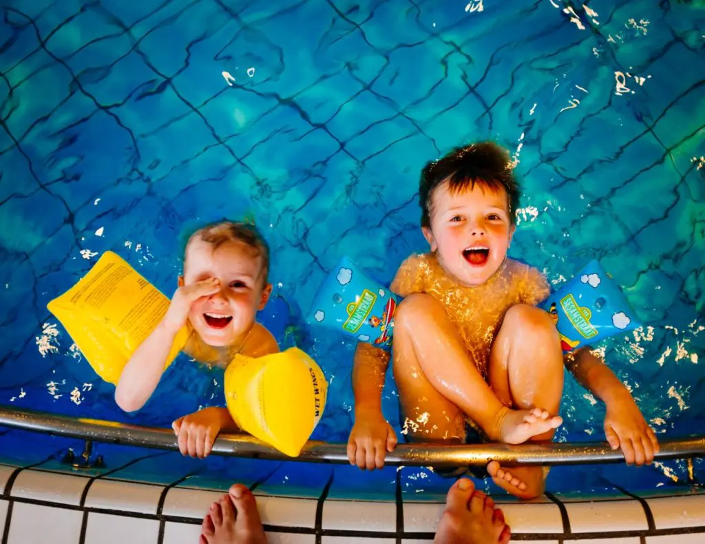 deux enfants heureux dans une piscine hors sol avec accessoires de baignade jaunes