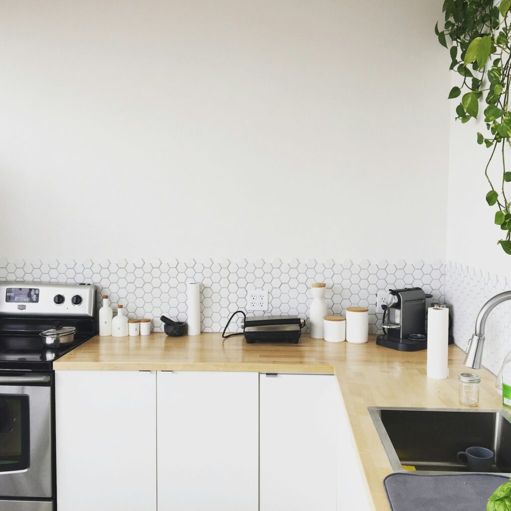 cuisine minimaliste avec carrelage hexagonal blanc, plan de travail bois clair et rangements épurés