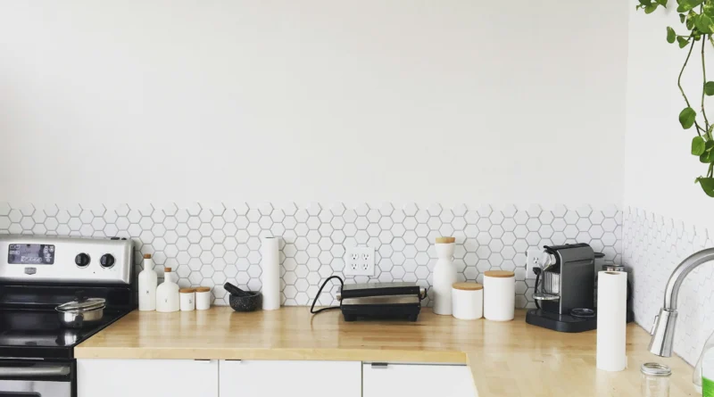 cuisine minimaliste avec carrelage hexagonal blanc, plan de travail bois clair et rangements épurés