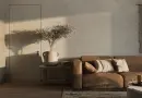 Warm minimalist living room featuring a brown sofa and decorative elements.
