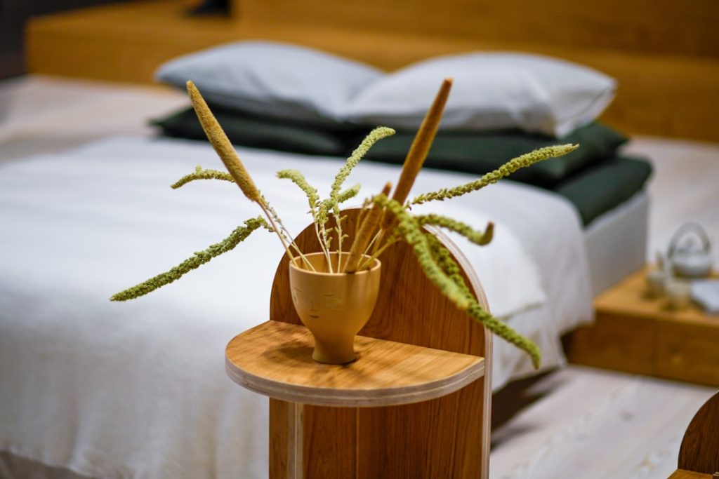 Dried grass in a wooden vase on a bedside table.