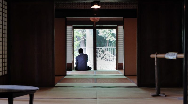 A person sits on the floor in a traditional room.