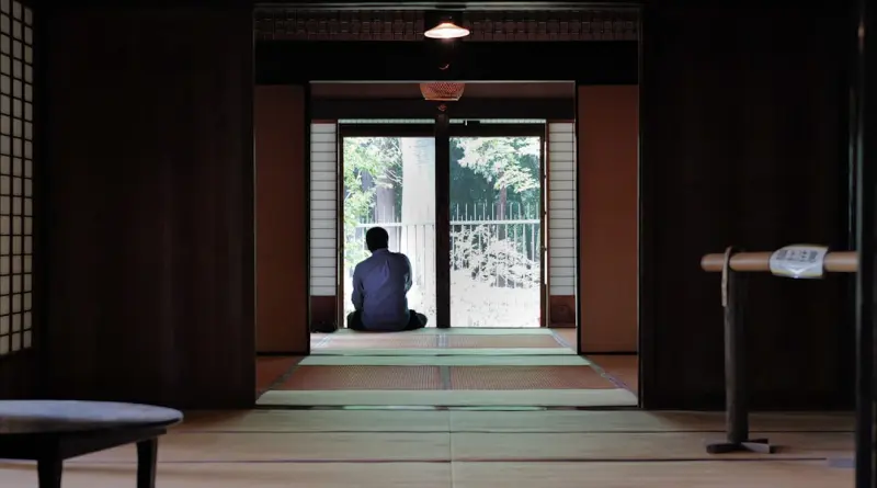A person sits on the floor in a traditional room.